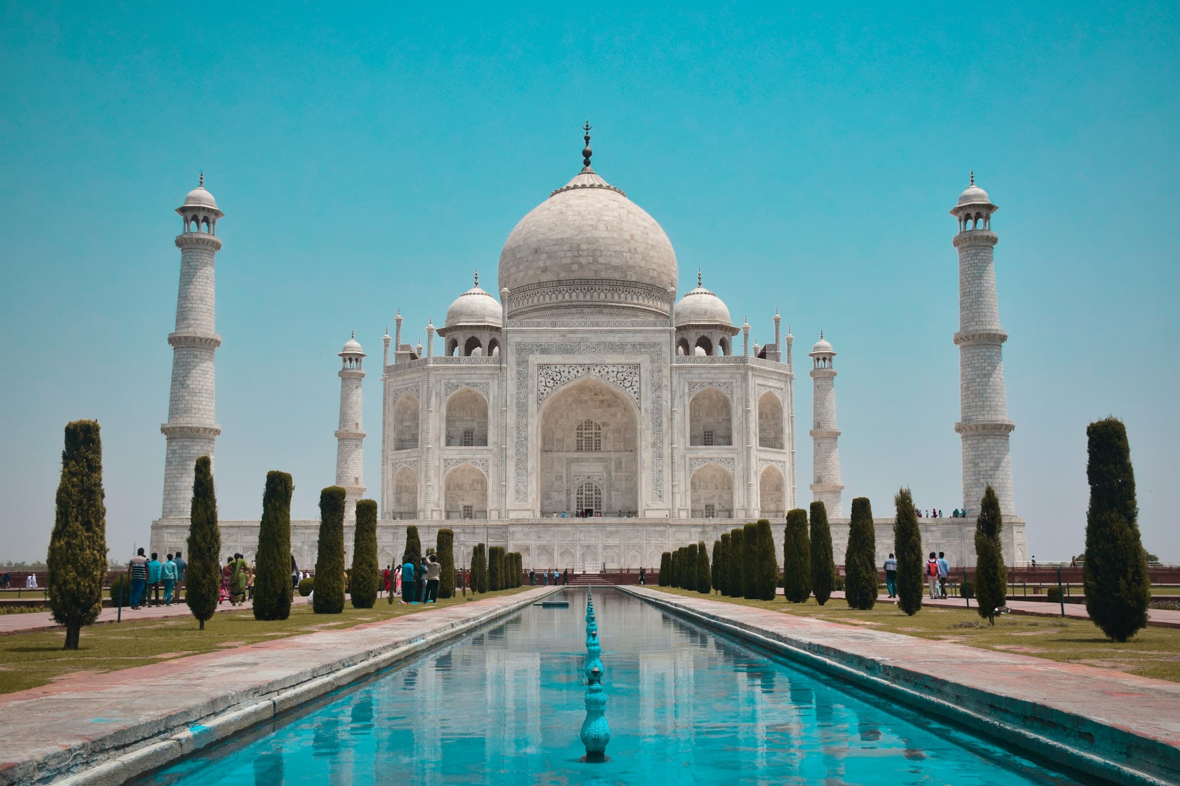 The Taj Mahal reflected in its gardens beneath a blue sky